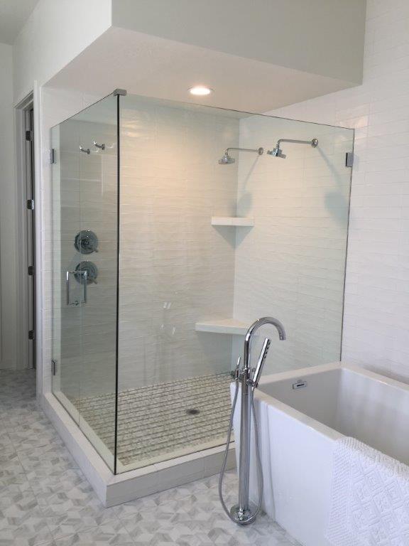 A bathroom with a glass shower door and tub, showcasing a modern and sleek design.


