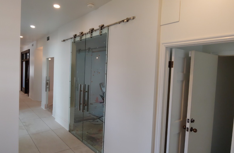 Glass doors line the hallway in a house, leading to a bathroom door.


