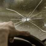 A person driving a car with a cracked windshield, in need of car auto glass replacement.