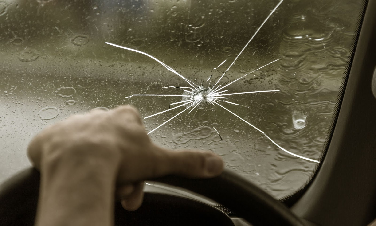 A person driving a car with a cracked windshield, in need of car auto glass replacement.
