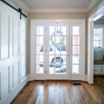 A hallway with white doors and hardwood floors, featuring various types of glass doors for your home.
