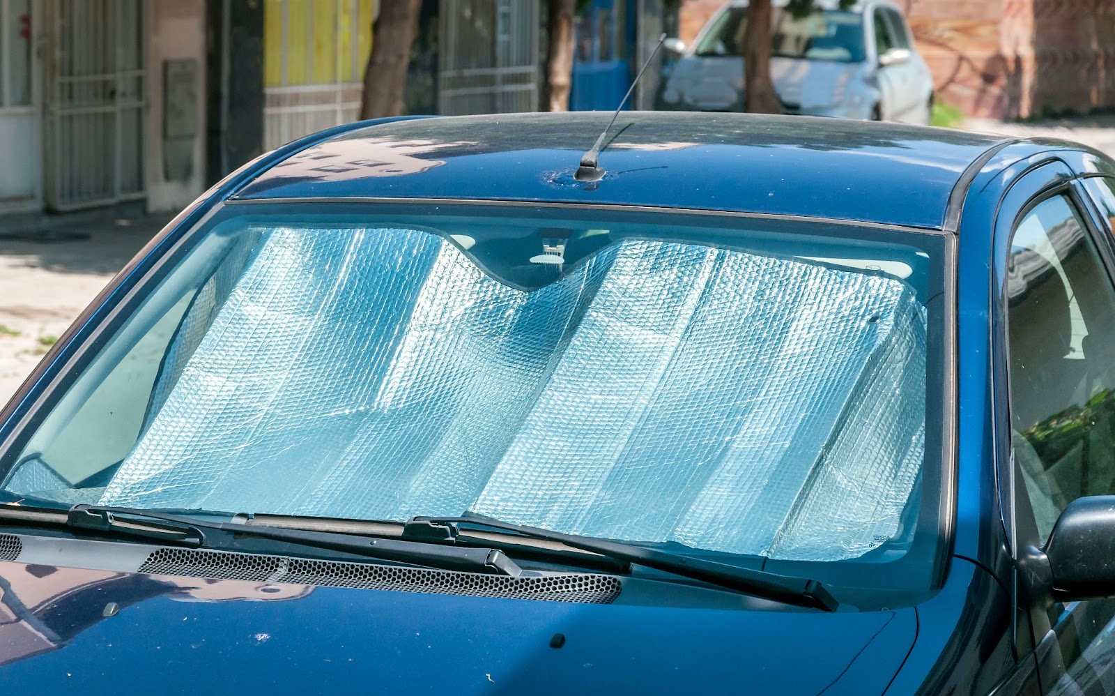 A blue car with a blue windshield, highlighting the importance of windshield replacement in summer heat conditions.