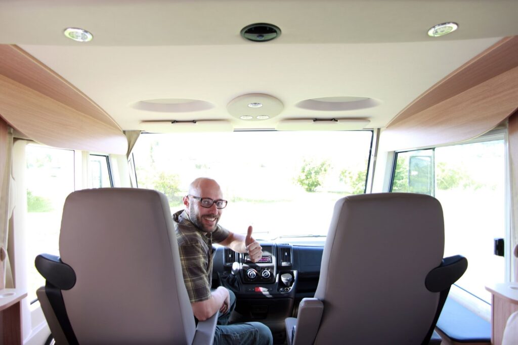 A man seated in the driver's seat of a van, focusing on the windshield replacement process for a broken motorhome windshield.