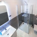 A modern bathroom featuring a shower, toilet, sink, and stylish mirrors, showcasing a recent residential upgrade.