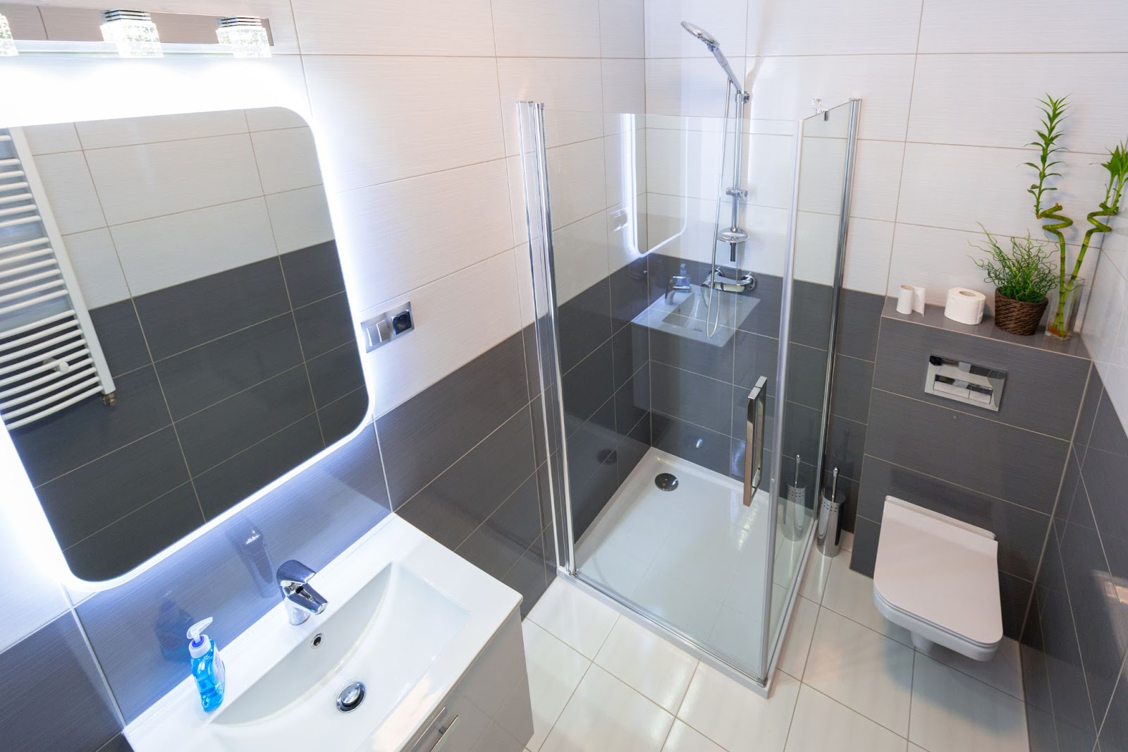 A modern bathroom featuring a shower, toilet, sink, and stylish mirrors, showcasing a recent residential upgrade.