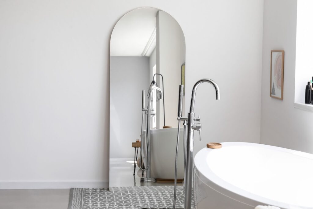 A spacious bathroom featuring a large mirror above a stylish tub, ideal for a residential upgrade.