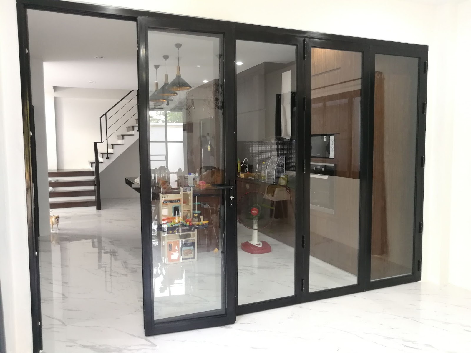 A large glass sliding door beside a staircase, featuring durable aluminum windows and street car window designs.